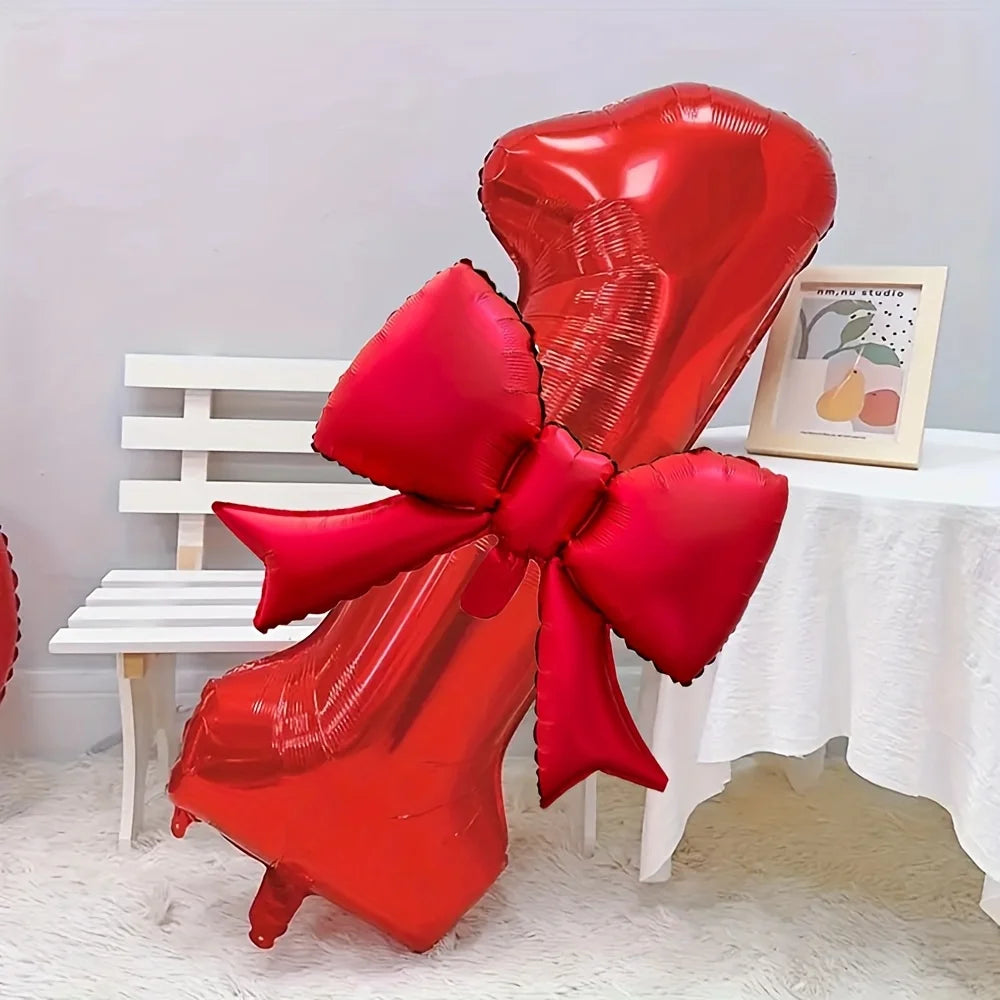 A large red foil balloon shaped like a heart with a matching bow, displayed on a white table.