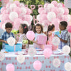 A table decorated with pink and white balloons and pink gift boxes for a celebration.