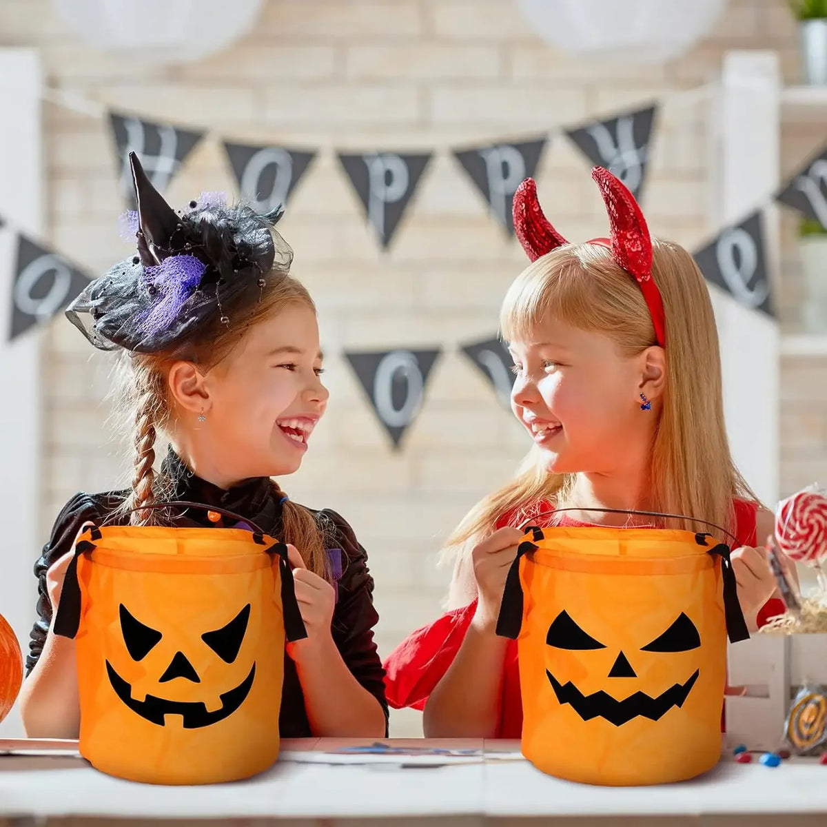 Two girls smiling while holding orange Halloween pumpkin tote bags with LED light-up handles.