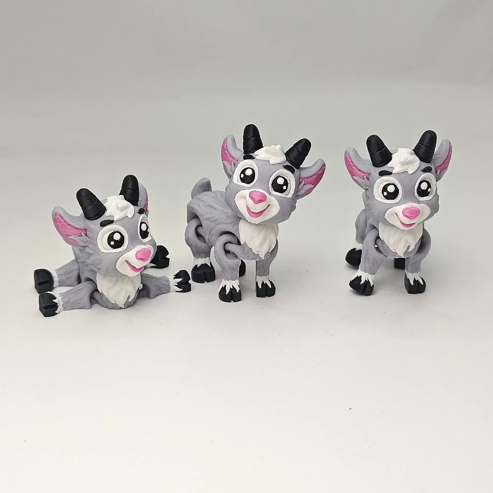 Three 3D printed goat figurines in gray and pink standing or lying down.