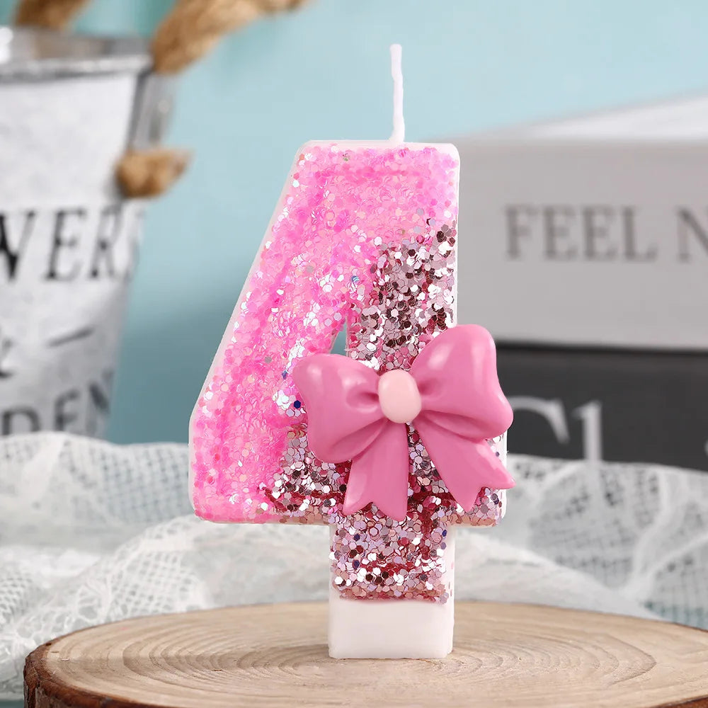Pink glitter number candle shaped like 4 with a pink bow on a white base