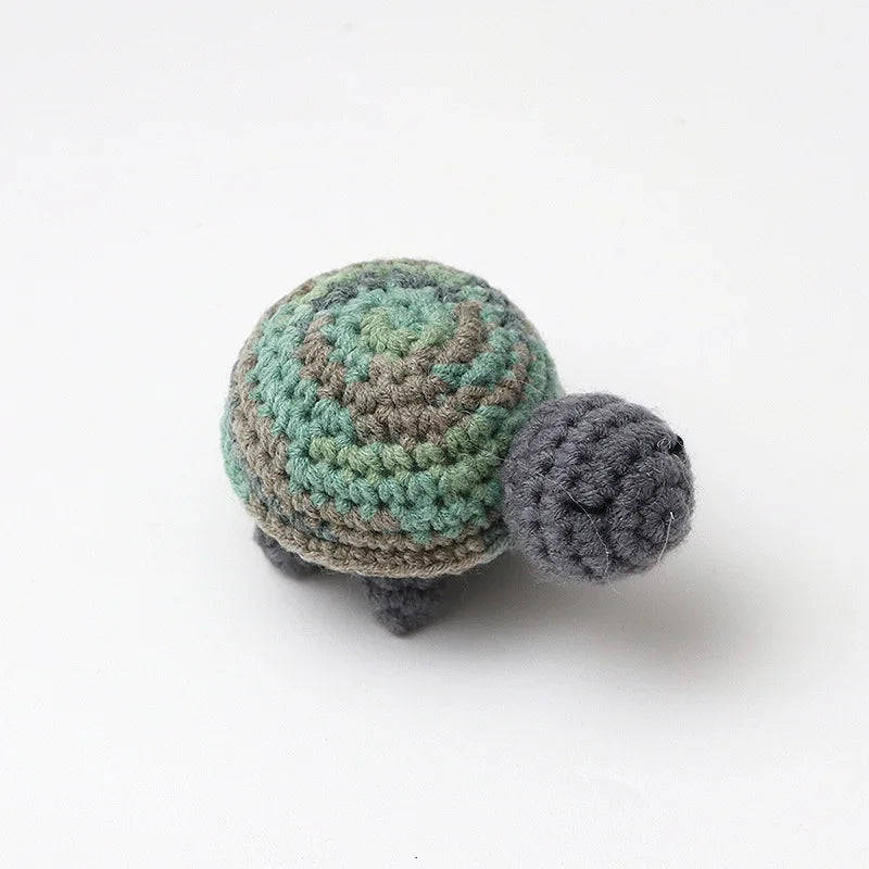 Handmade crocheted turtle plush with mottled green and gray scales.