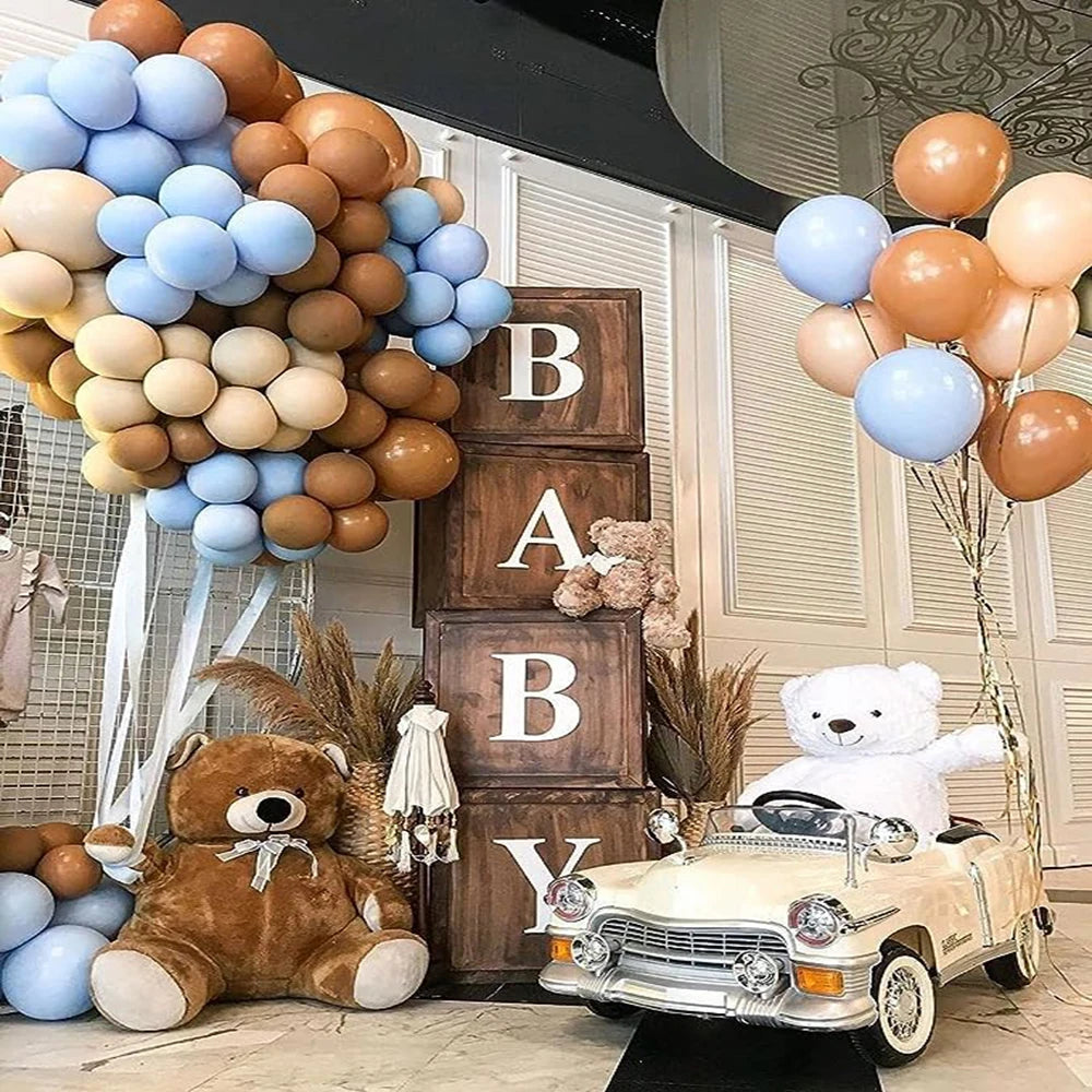 A display featuring brown and blue latex balloons, teddy bears, and a vintage car set against a white background.
