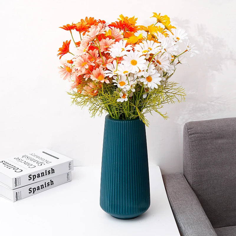 A vase filled with orange, white, and yellow flowers sits on a white surface.