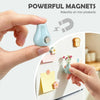 A hand holds a small, light blue ceramic magnet that is adhering to a white surface with colorful sticky notes.