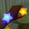 A hand holds a glowing purple LED star light, illuminating the surrounding area.