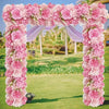 A floral archway decorated with pink and white silk roses for a wedding or event backdrop.