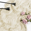 A light blue cheesecloth table runner is draped on a surface with dark, decorative metal utensils and pink roses.