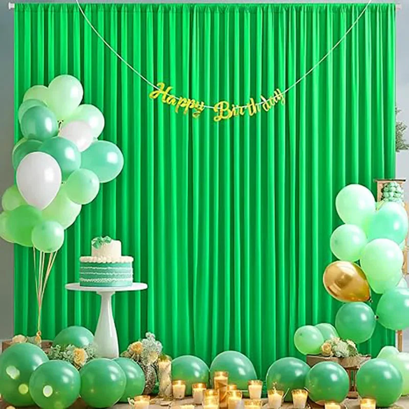 A vibrant green curtain backdrop decorated with gold balloons spelling out Happy Birthday and various green and white balloon