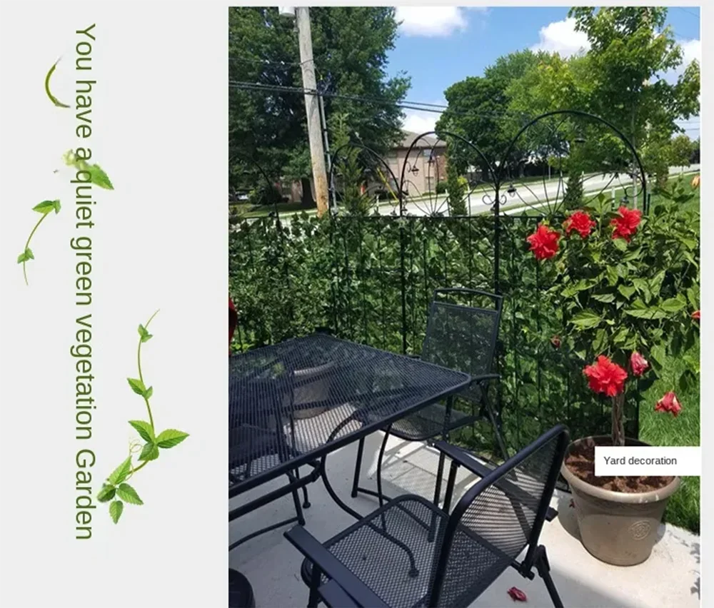 Black artificial ivy hedge fence panels growing vibrant red roses in a garden setting.
