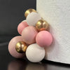 A set of pink and gold ball decorations for a cake topper, featuring various shades of pink and cream.