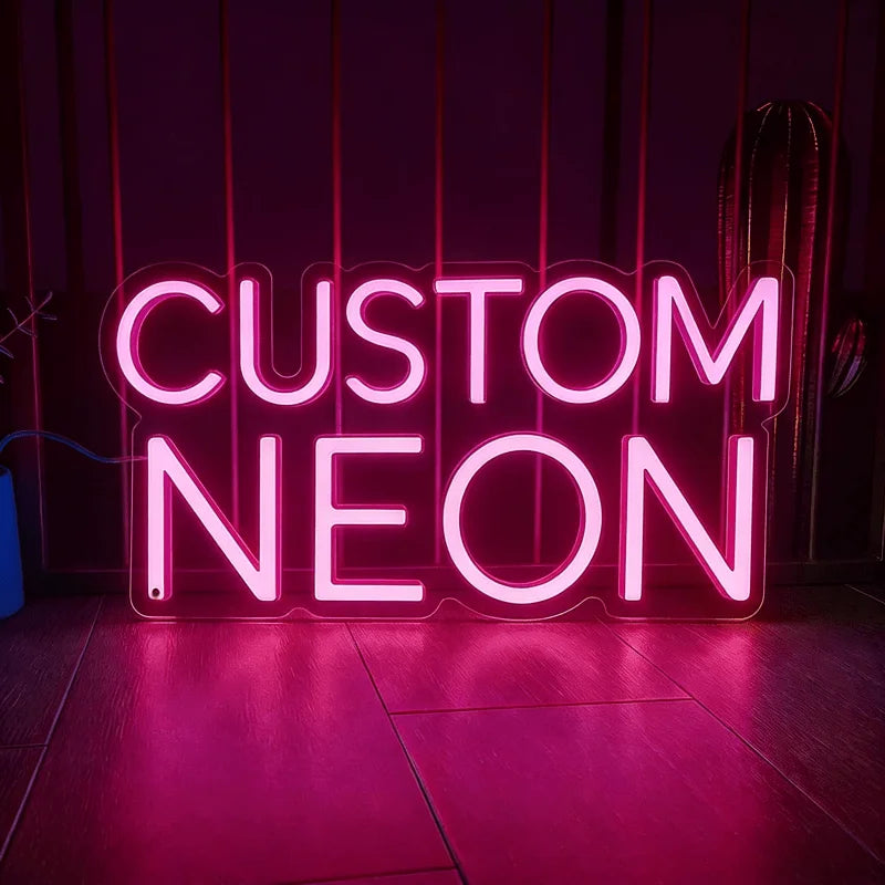 A glowing pink neon sign spelling out CUSTOM NEON on a dark background.