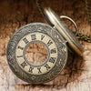 A vintage bronze quartz pocket watch with an ornate dial and chain resting on a wooden surface.