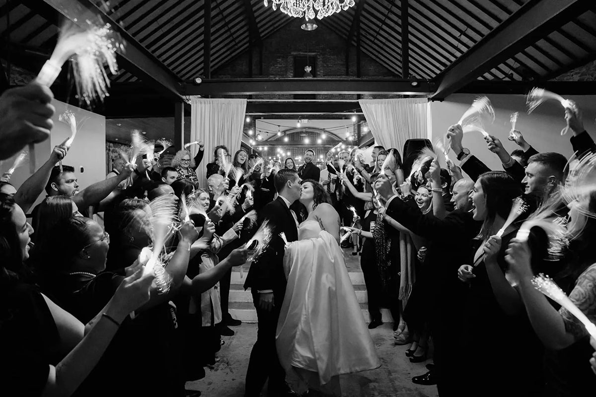 A group of people celebrating indoors with fiber optic LED glow wands in a party setting.