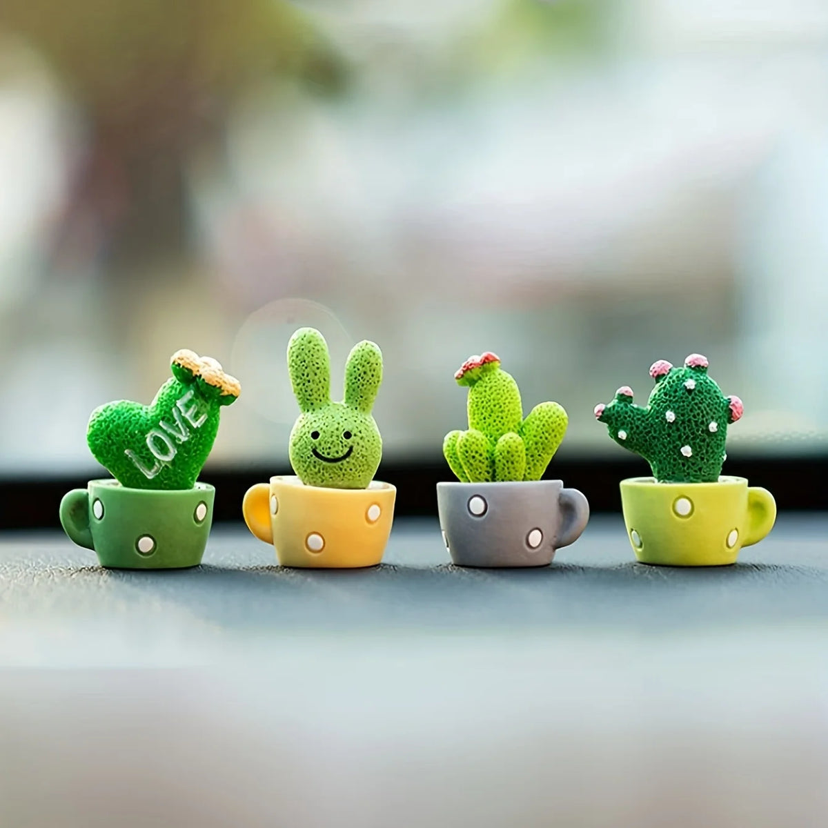 A set of four resin succulent cacti in various shades of green and yellow sitting in small cups for home decor.