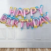 A garland of 13 foil letter birthday balloons spelling out HAPPY BIRTHDAY across a white door.