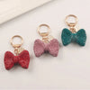 A set of sparkling rhinestone bow keychains in red, pink, and teal colors.