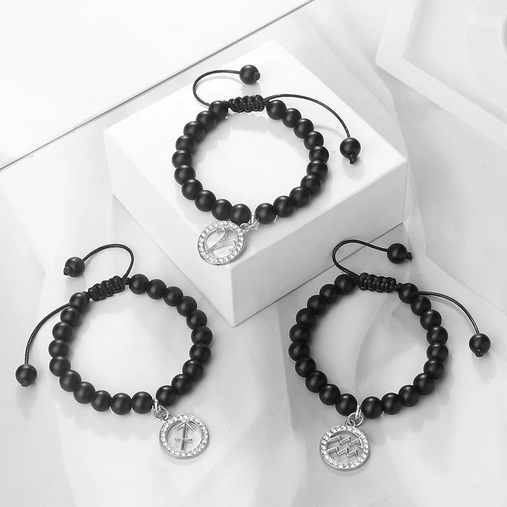 A black beaded bracelet with a silver zodiac charm displayed on a white box.