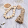 A handmade wood and jute bead garland is displayed on a white cloth next to a cup of coffee.