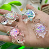 Several glow-in-the-dark mini sea turtle figurines are held in a hand, showcasing iridescent and colorful details.