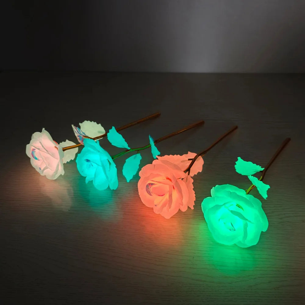 A collection of glowing, translucent roses in pink, blue, and orange light against a dark surface.