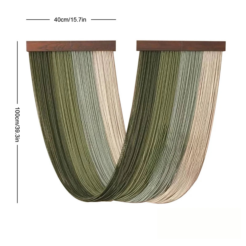 Boho macrame wall tapestry featuring vertical strands in shades of olive green and beige.