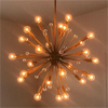 A modern chandelier with multiple arms and exposed filament bulbs hangs against a light wall.