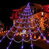 A Christmas tree shape made of purple LED lights illuminates a house decorated for Halloween.