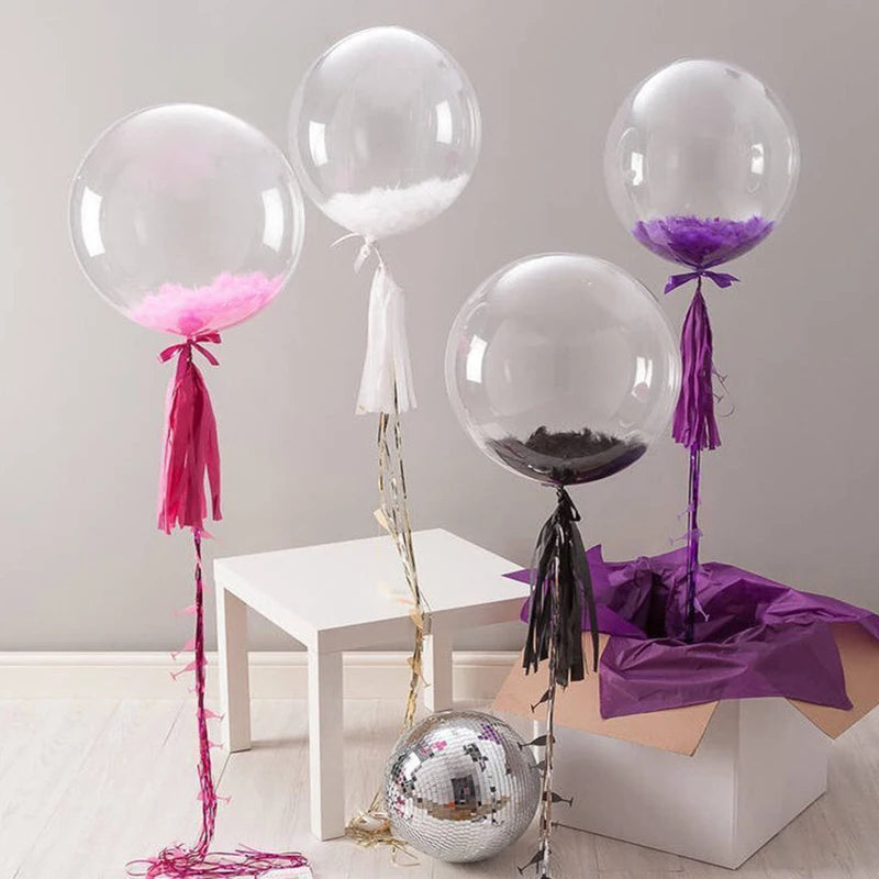 A display of clear bubble balloons in pink, purple, and silver, tied with ribbons on a white table.
