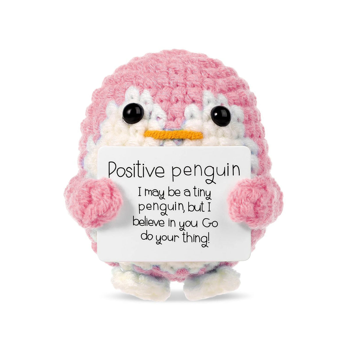 A pink and white crocheted penguin plush toy holding a card with an encouraging message.