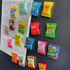 A collection of colorful candy-shaped refrigerator magnets including Lay's, Bugles, Cheetos, and Takis.