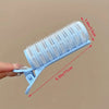 A hand holds a light blue heat-free curling set with numerous thin plastic rods for DIY hair styling.
