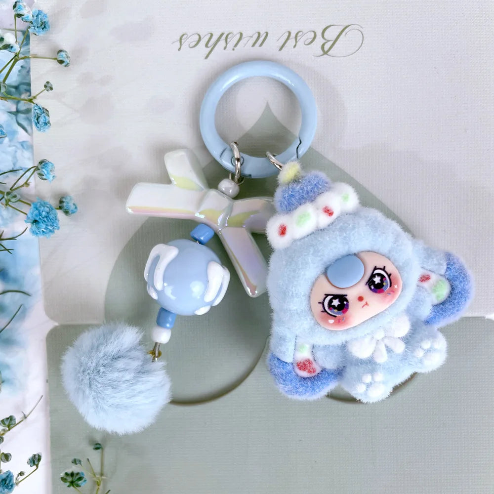 A fluffy blue heart plush keychain charm with a light purple wing and a blue bead on a silver ring.