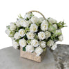 A bouquet of white artificial roses with green foliage in a woven basket.