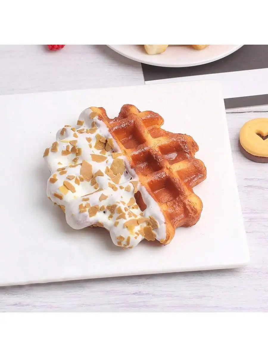 A golden waffle topped with white cream and chopped nuts served on a white plate.