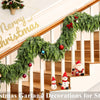 A festive Christmas garland decorated with evergreen branches, ornaments, and Santa figures adorning a wooden staircase.