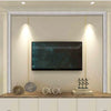 A flat-screen television is mounted within a decorative frame on a wall above a wooden cabinet.