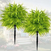 Two artificial green Persian fern stakes displayed outdoors in a garden setting.