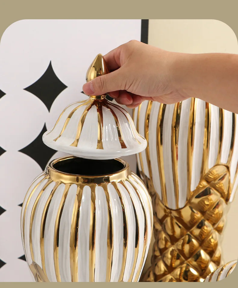 A hand is placing a gold-rimmed ceramic lid onto a white and gold striped decorative vase.