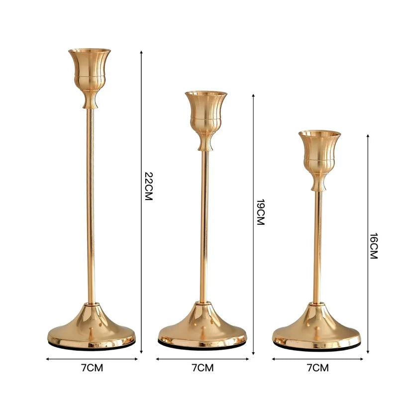 Set of three elegant gold metal candlesticks with flared bases and slender stems