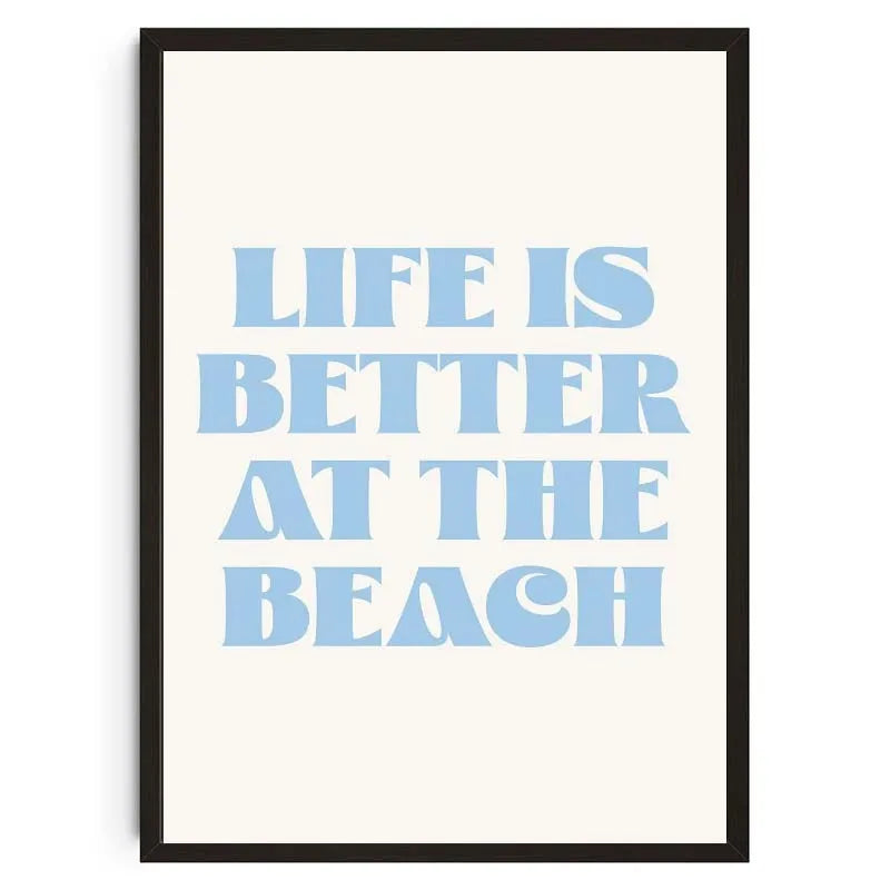 Gerahmtes Druck mit dem Text 'Life is better at the beach' in hellblauer Schrift auf weißem Hintergrund.