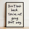 Black handwritten quote on white canvas print saying Don't look back. You're not going that way.