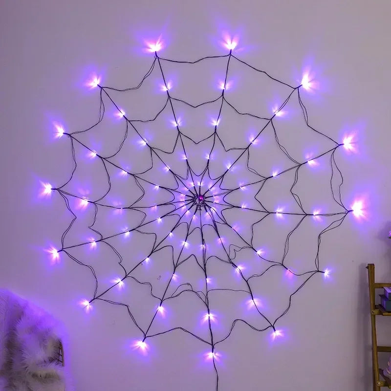 A glowing purple spider web pattern made of LED string lights on a white wall.