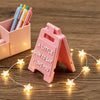 A pink 3D lettering sign shaped like an arrow with the text A LITTLE SIGN TO SAY I LOVE YOU resting on a wooden surface.