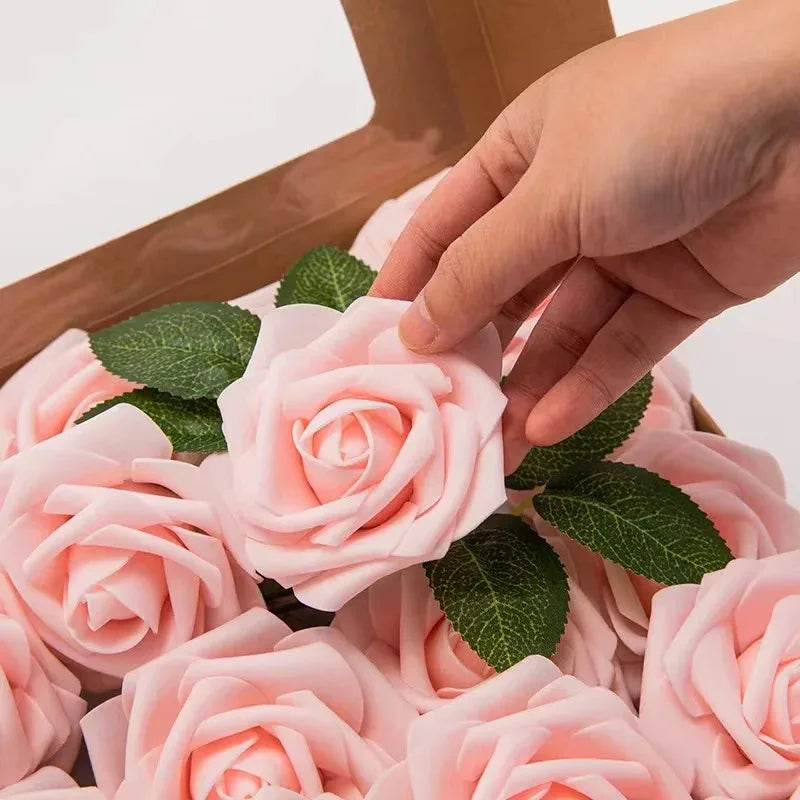 A hand is placing pink foam roses into a box for wedding and home décor.