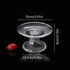 Clear acrylic serving plate with a decorative pedestal base and a small red fruit.