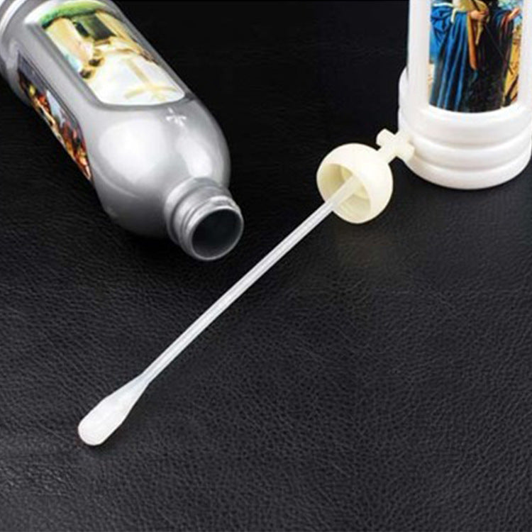 A glass bottle of glow-in-the-dark holy water with a dropper and liquid on a black surface.