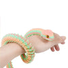 Eine Hand hält ein flexibles, buntes 3D gedrucktes Schlangen-Fidget-Spielzeug mit rosa und grünen Schuppen.