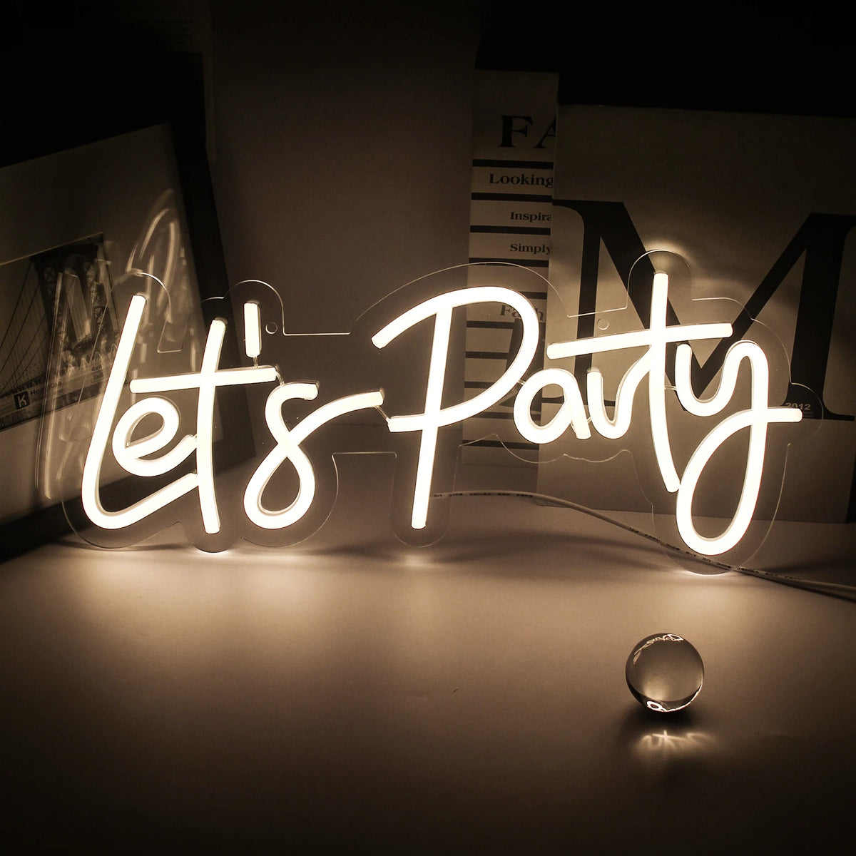 A glowing neon sign spelling out Let's Party on a dark surface with blurred background elements.