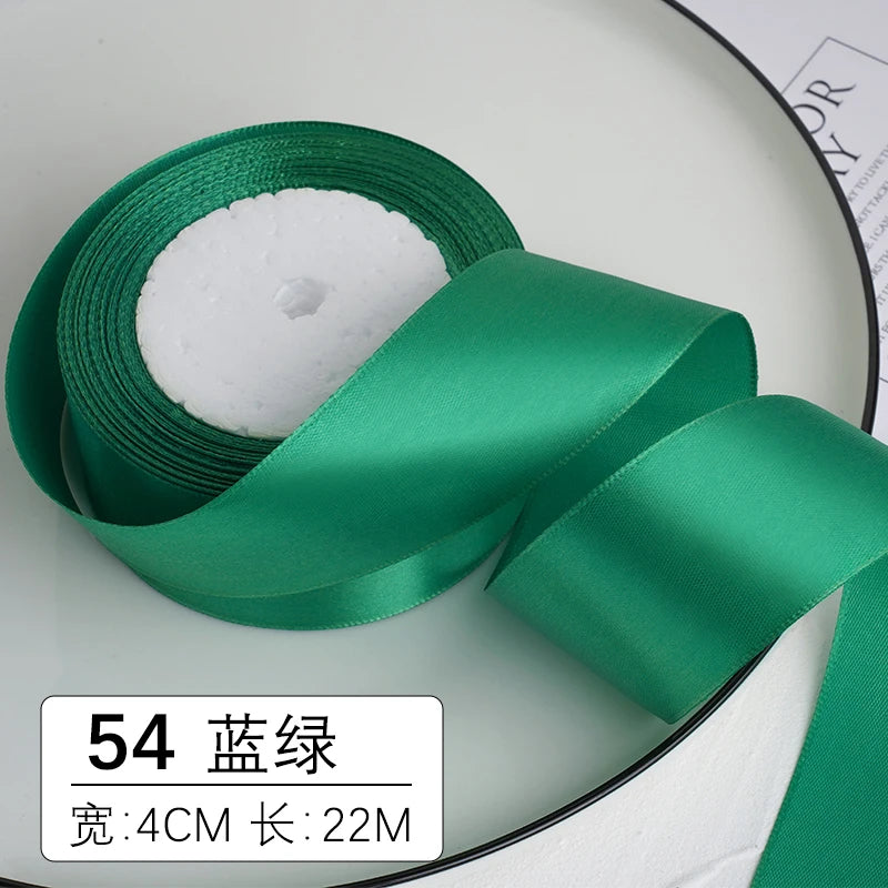 Un rouleau de ruban décoratif satin vert émeraude avec un noyau blanc et une étiquette indiquant 54 mètres.